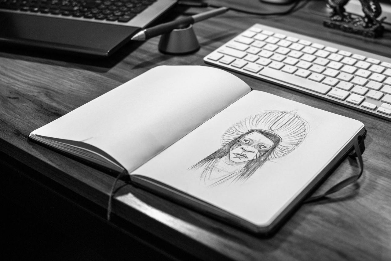 The Art of Drawing Readers In: Your attractive post title goes here Monochrome image of a sketchbook with a pencil drawing on a wooden desk with laptop and keyboard.